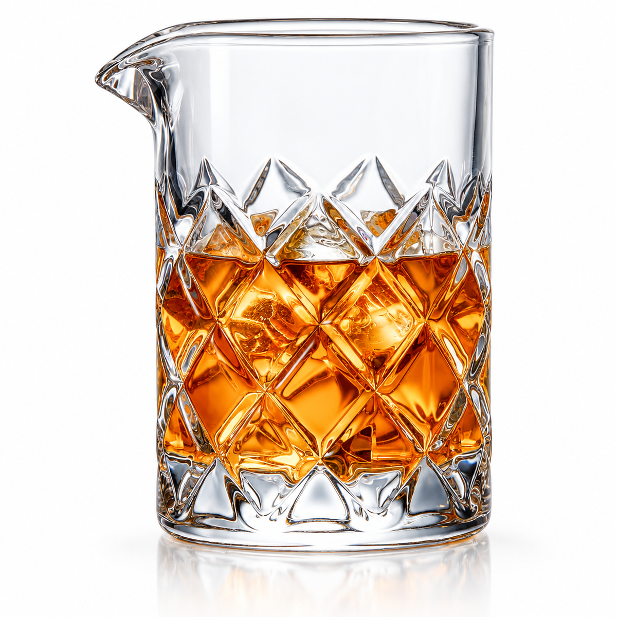 Diamond cut crystal mixing glass filled with an amber cocktail and ice