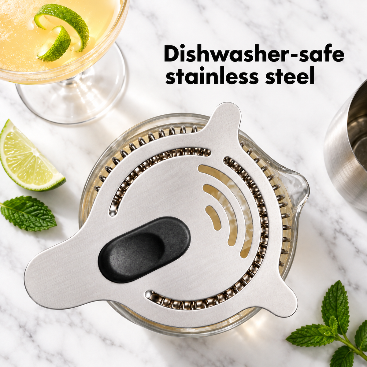 Hawthorne strainer sitting on a mixing glass with lime and mint