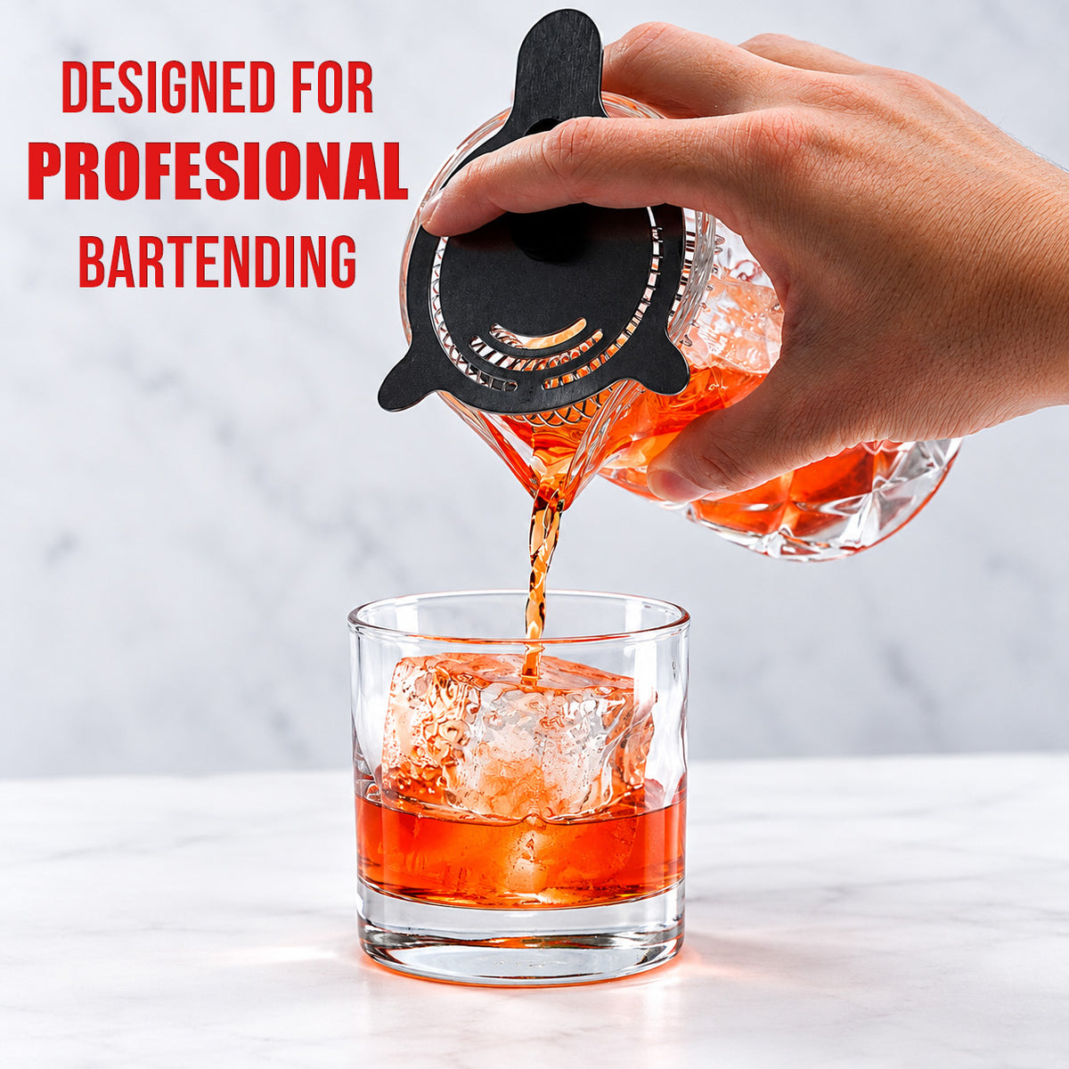 Pouring a stirred cocktail from the mixing glass through a julep strainer into a rocks glass