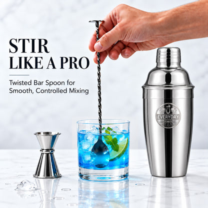 Stirring a blue cocktail with the twisted bar spoon next to the shaker and jigger