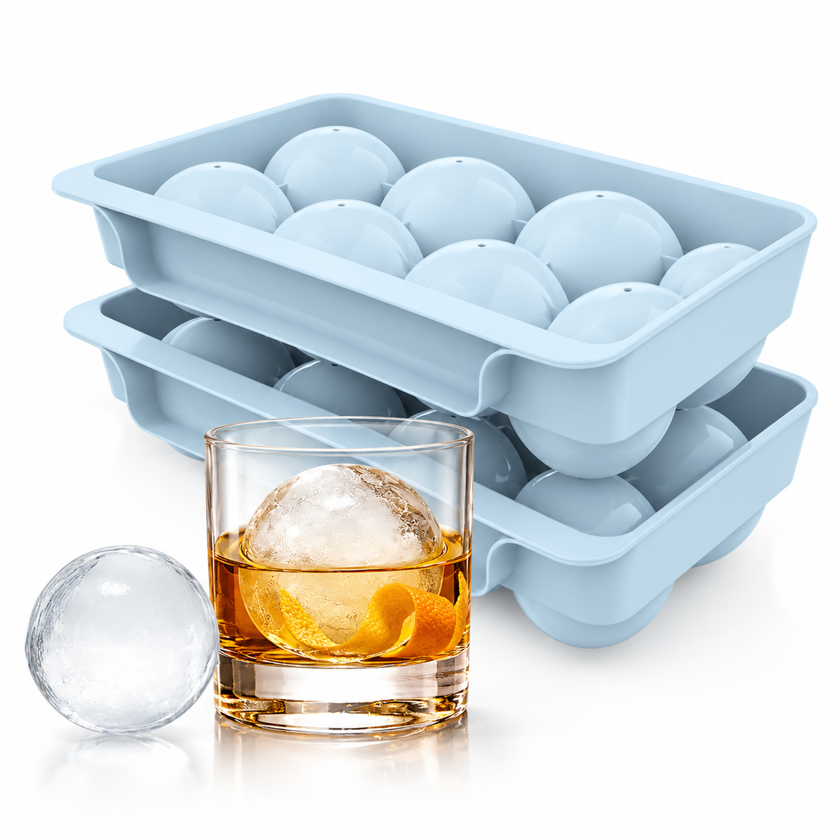 Ice ball mold trays with a large clear ice sphere in a whiskey glass